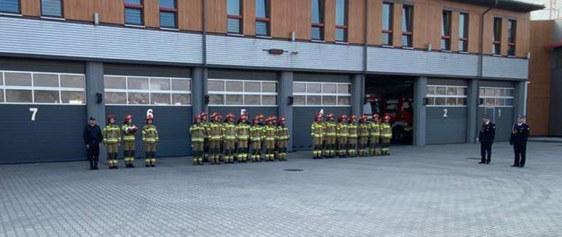 Strażacy na placu, po lewej samochód gaśniczy