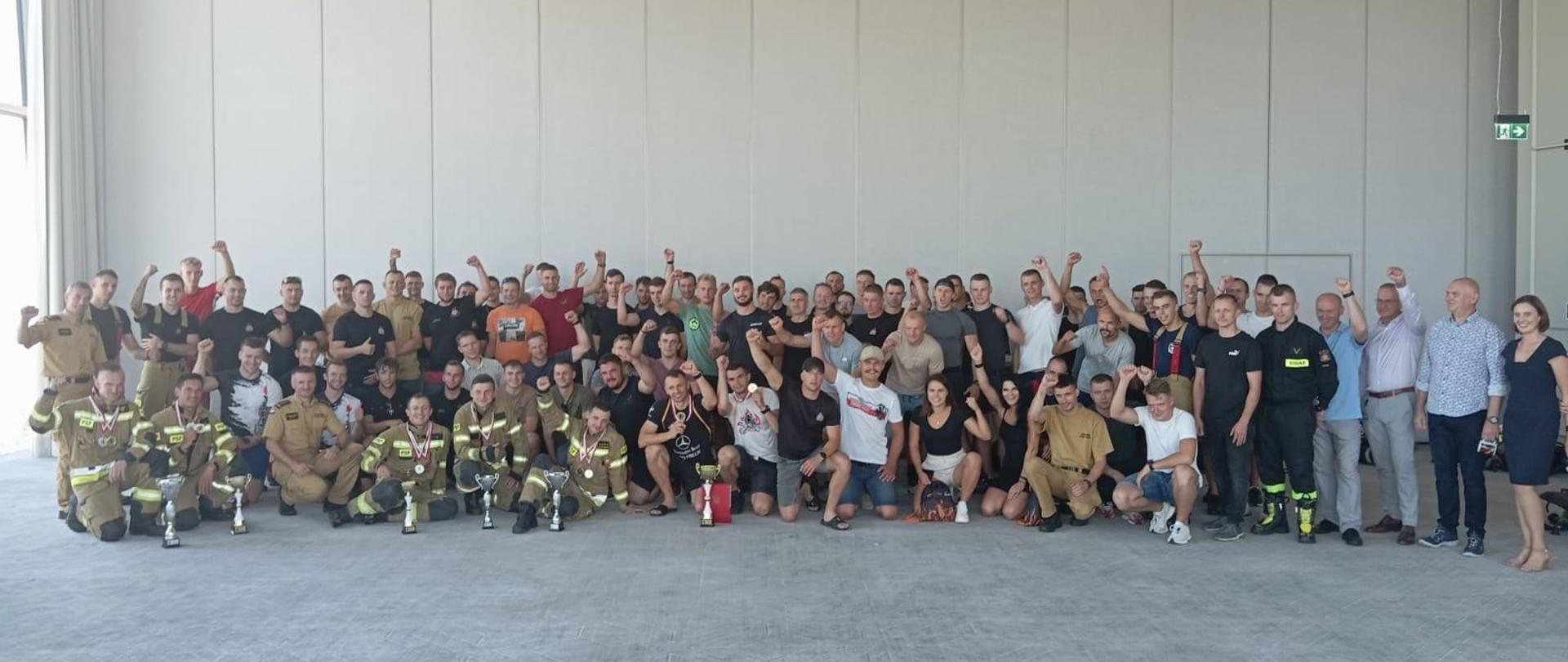 Na zdjęciu strażacy i organizatorzy po zakończeniu biegu pozują do pamiątkowego zdjęcia na 34 piętrze. 