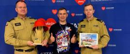 Strażacy przekazujący przedmioty na aukcję WOŚP