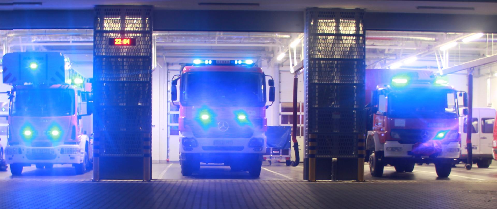Samochody strażackie w garażu z włączonymi sygnałami świetlnymi