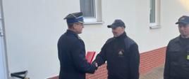 Zdjęcie przedstawia Komendanta Powiatowego PSP oraz Zbigniewa przechodzącego na zaopatrzenie emerytalne