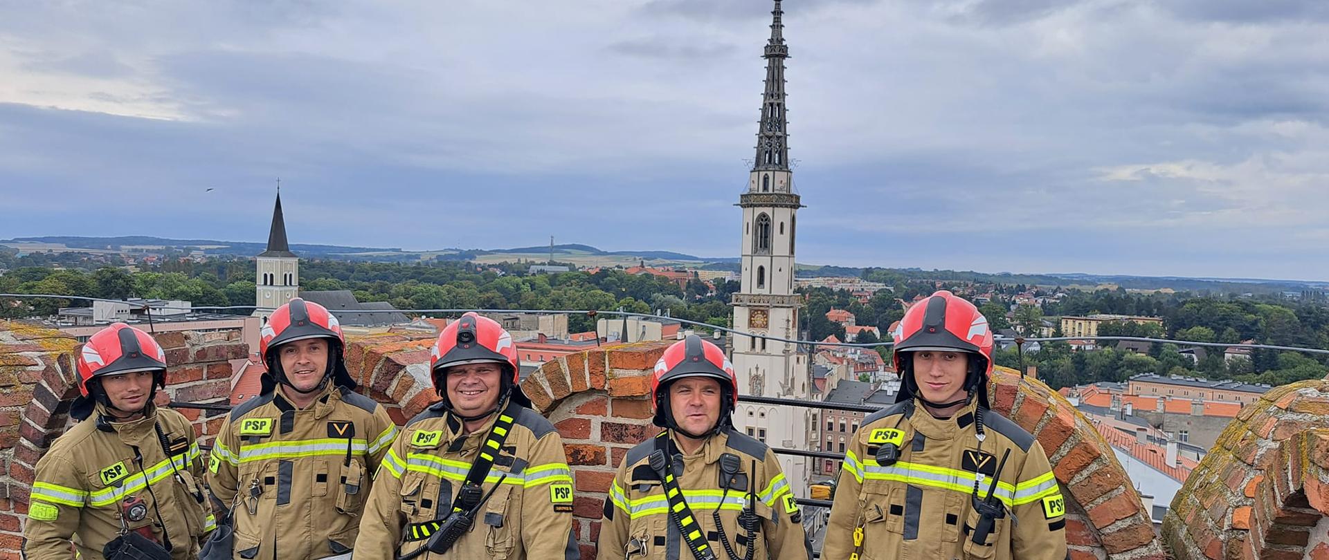strażacy stoją na górnej kondygnacji na krzywej wieży w Ząbkowicach Śl.
