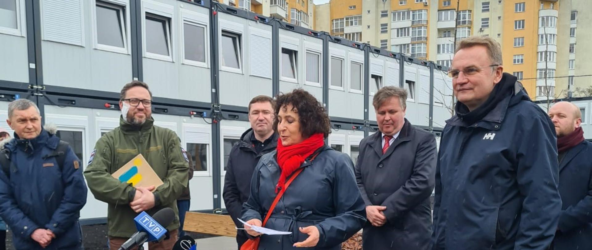 Grupa osób na tle domów modułowych