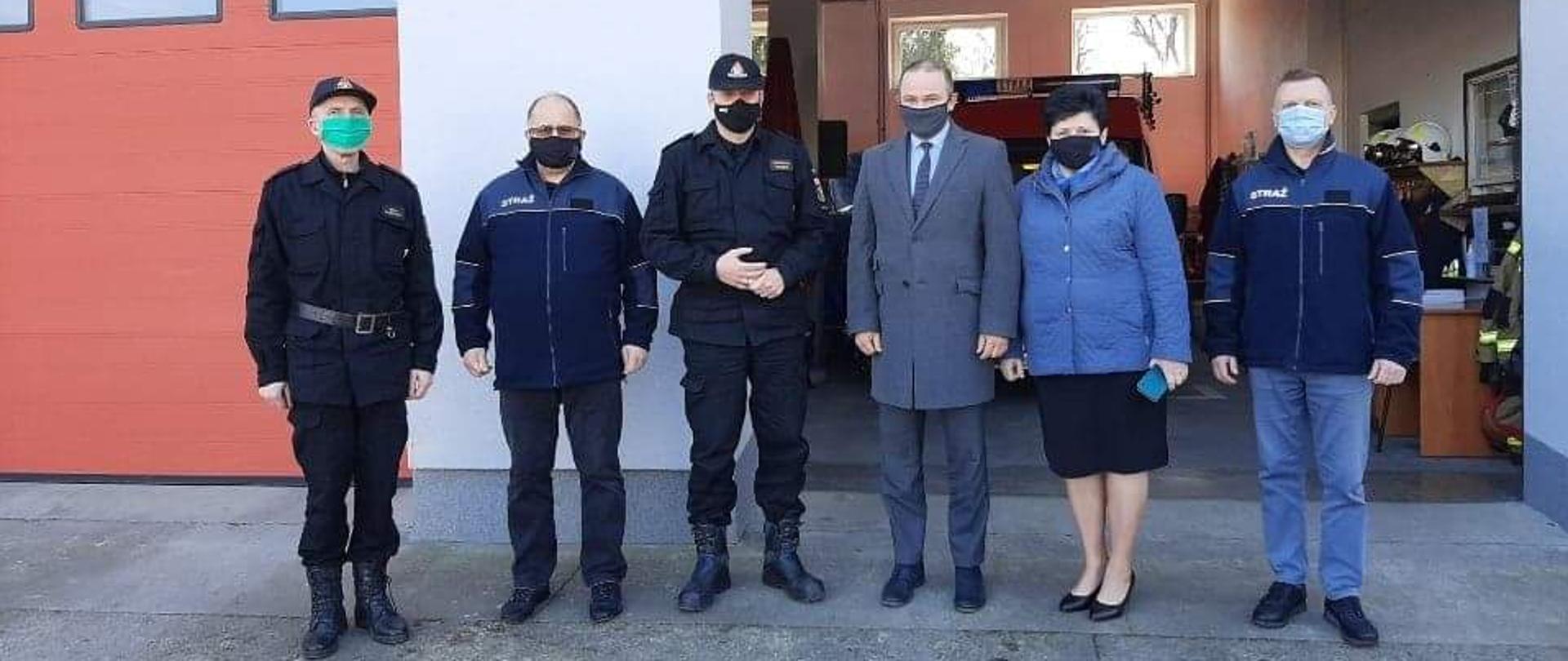 Na pierwszym planie zaproszeni goście wraz z komendantem wojewódzkim PSP w tle garaż jednostki OSP