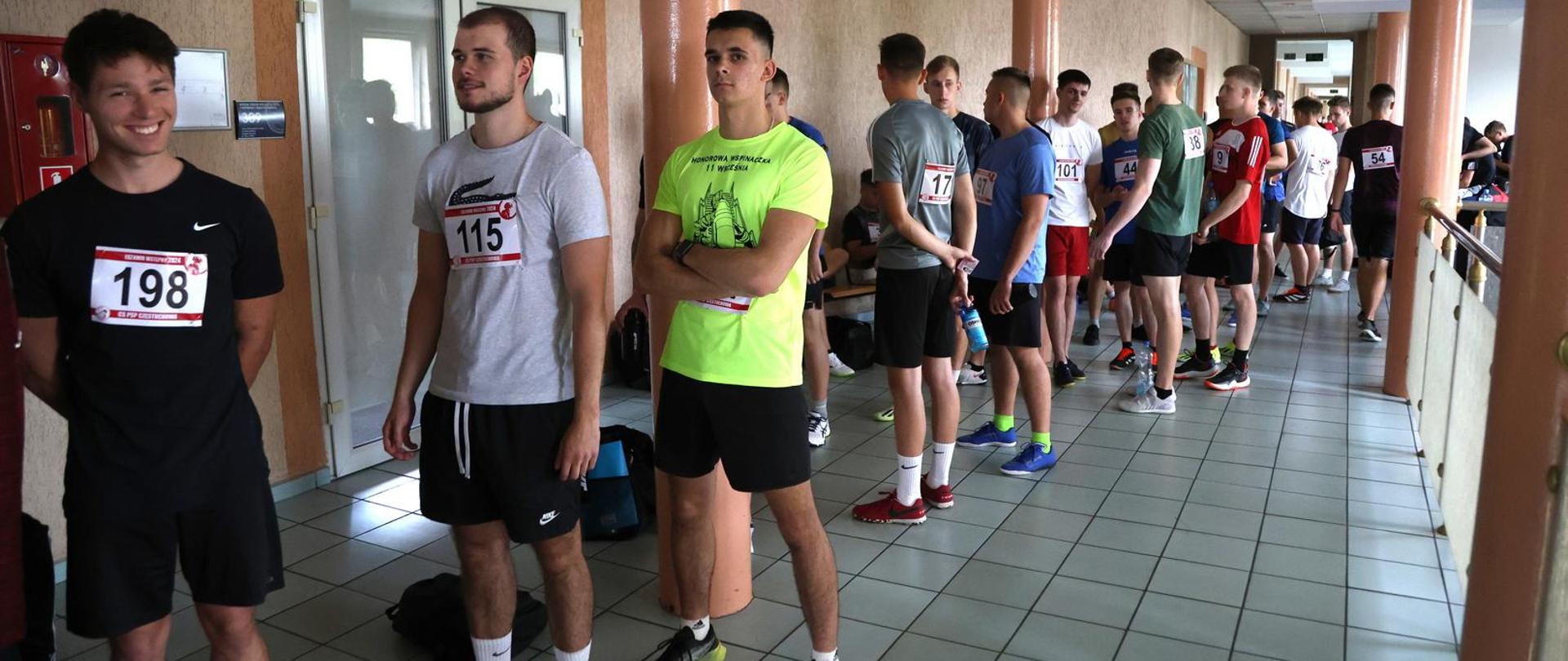 Kandydaci przybyli do Centralnej Szkoły PSP na testy sprawności fizycznej stojący w kolejce w oczekiwaniu na konkurencję bieg po kopercie