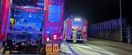Zdjęcie przedstawia samochody straży pożarnej na ulicy podczas dzialań gaśniczych.
