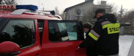 Na zdjęciu widnieją strażacy transportujący osoby starsze na szczepienie przeciwko COVID-19. 