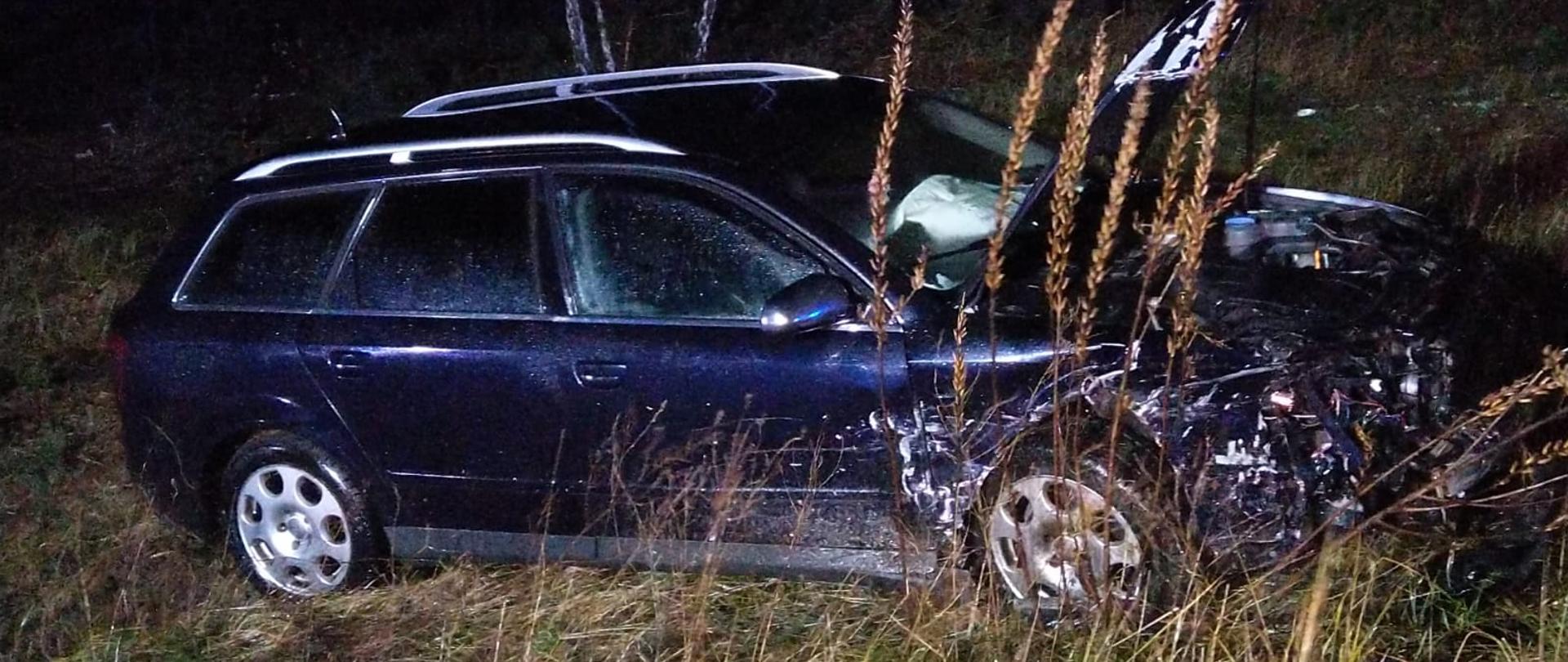 Samochód osobowy z rozbitym przodem stojący w trawie