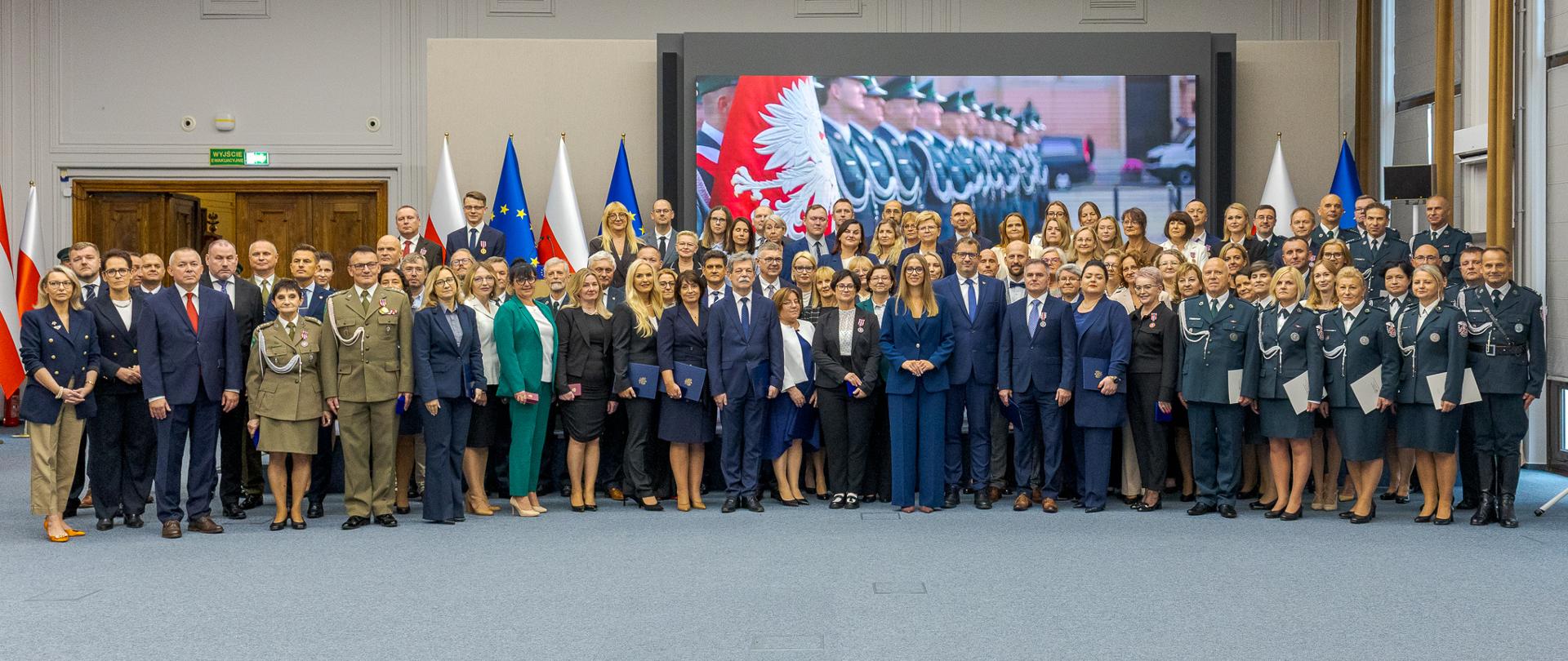 Wspólne zdjęcie uczestników centralnych obchodów KAS m.in. Minister Finansów i Gospodarki Andrzej Domański, wiceministrowie finansów: Szef KAS Marcin Łoboda, zastępca Szefa KAS Małgorzata Krok i zastępca Szefa KAS Zbigniew Stawicki. i inni uczestnicy centralnych obchodów Dnia Krajowej Administracji Skarbowej
