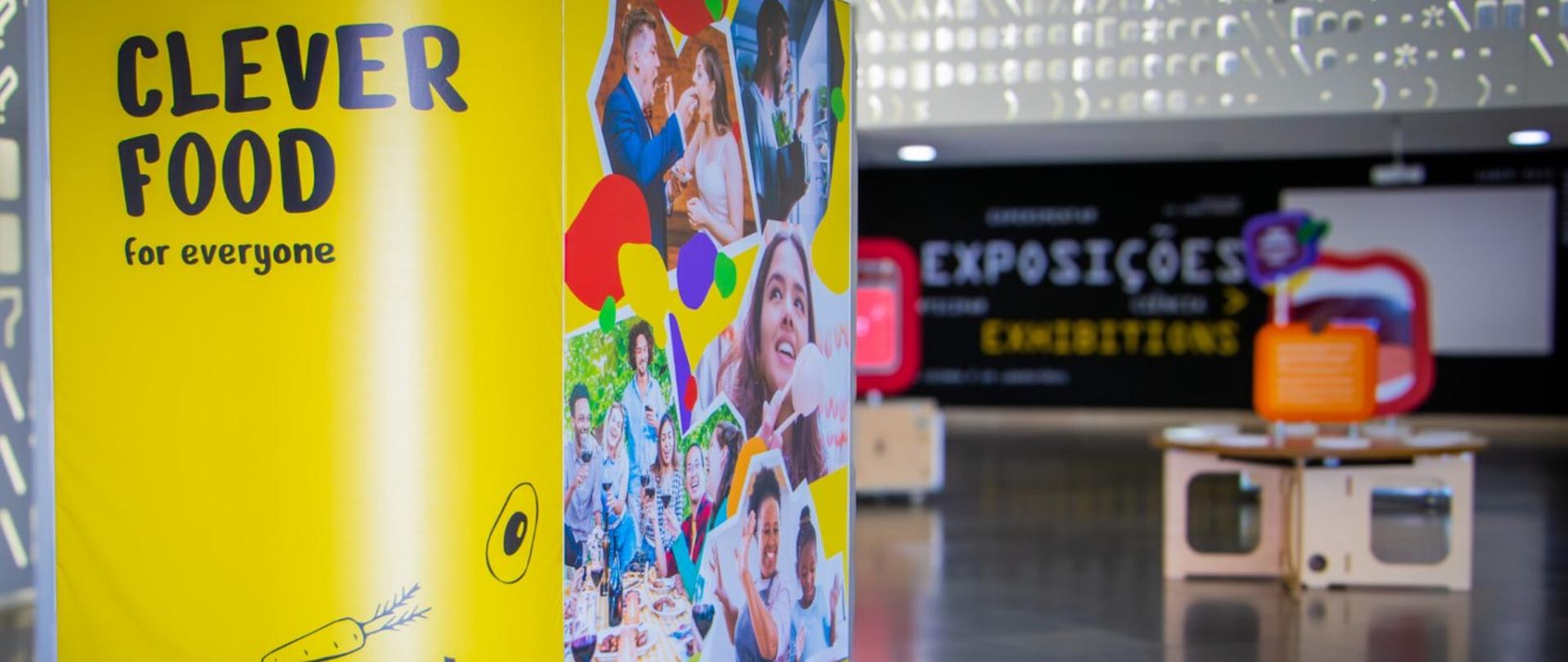 Plakat promujący wystawę CLEVERFOOD, w tle fragment ekspozycji
