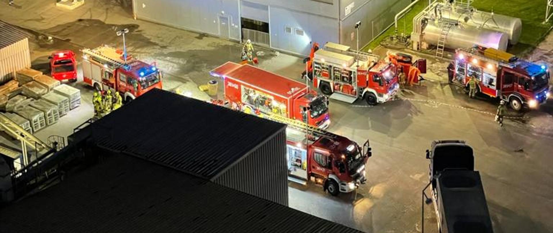 Samochody strażackie stoją na placu zakładu. Widok z lotu ptaka.