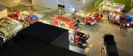 Samochody strażackie stoją na placu zakładu. Widok z lotu ptaka.