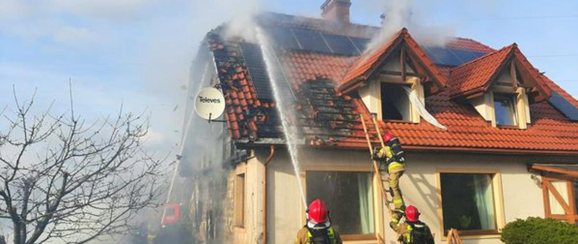 Zdjęcie przedstawia akcję gaśniczą, strażacy gaszący dom.