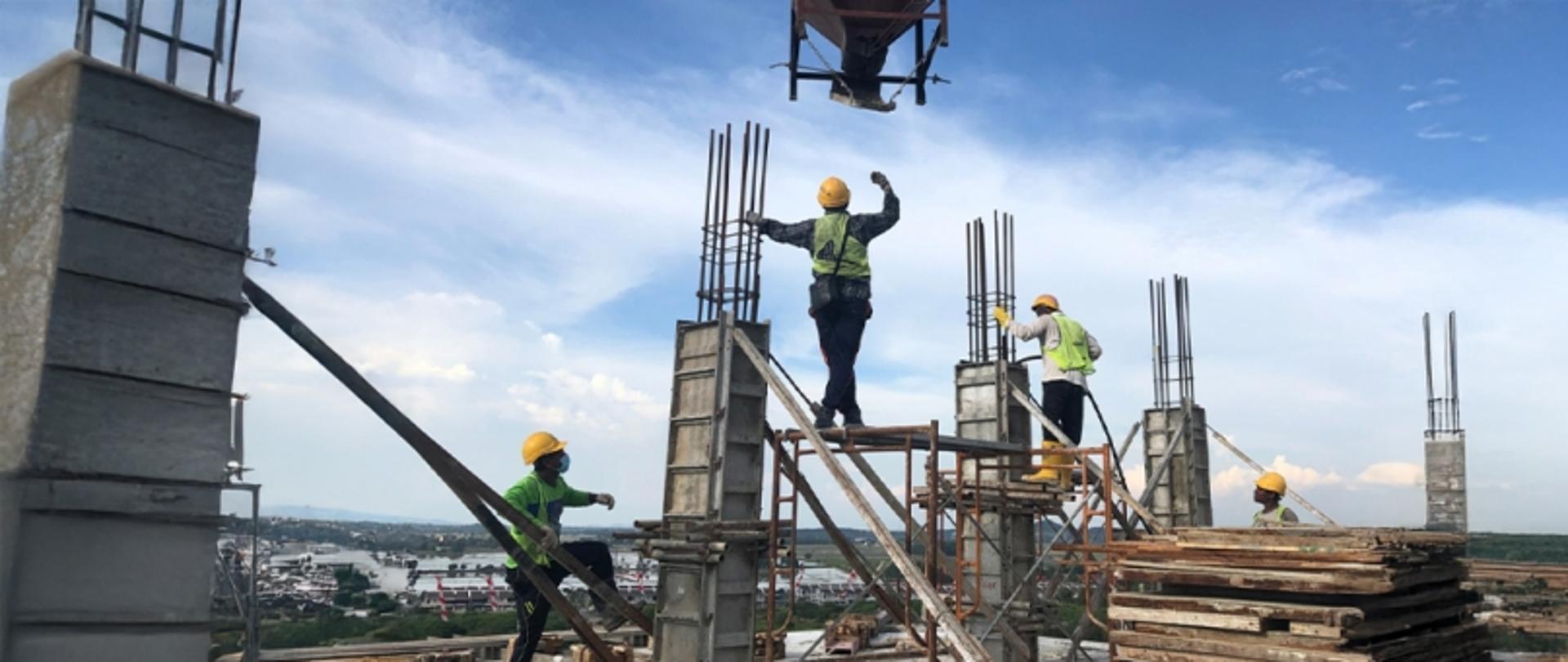 Na grafice po lewej stronie napis Ruch Budowlany w 2024 r. Pod spodem logo GUNB. Po prawej stronie na zdjęciu mężczyźni w kaskach budowlańcy, wspinają się po rusztowaniu na placu budowy. W tle widać błękitne niebo z chmurami. W prawym dolnym rogu na granatowym pasku adres strony gunb.gov.pl