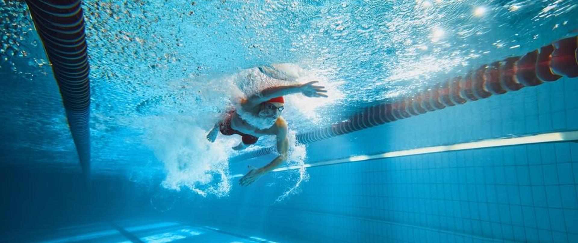Zdjęcie przedstawia osobę płynącą w basenie.