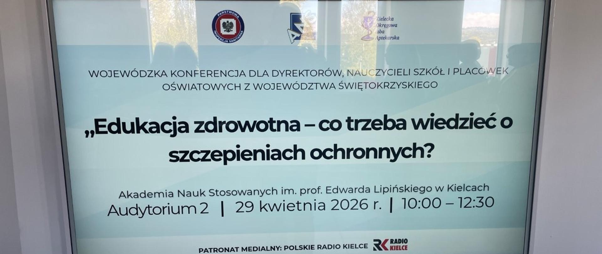 Ekran telewizora, na którym wyświetlony jest tytuł konferencji oraz logo organizatorów i nazwa patrona medialnego