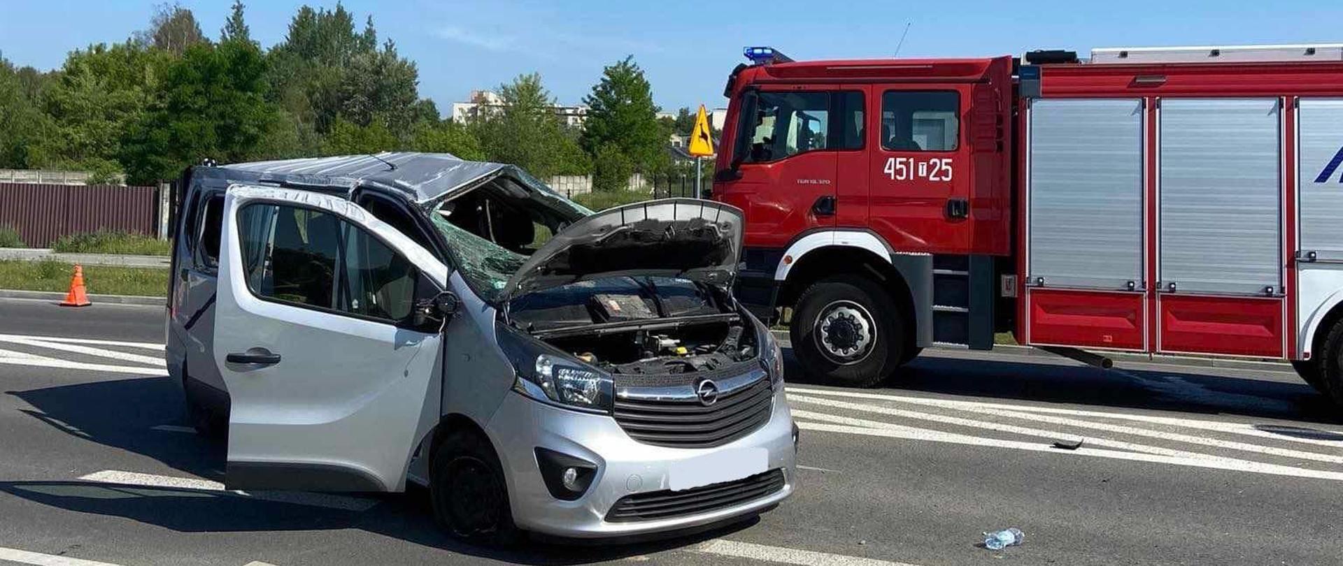 Na zdjęciu na pierwszym planie widoczny jest uszkodzony samochód marki opel vivaro, na drugim planie widoczny jest samochód ratowniczo - gaśniczy.