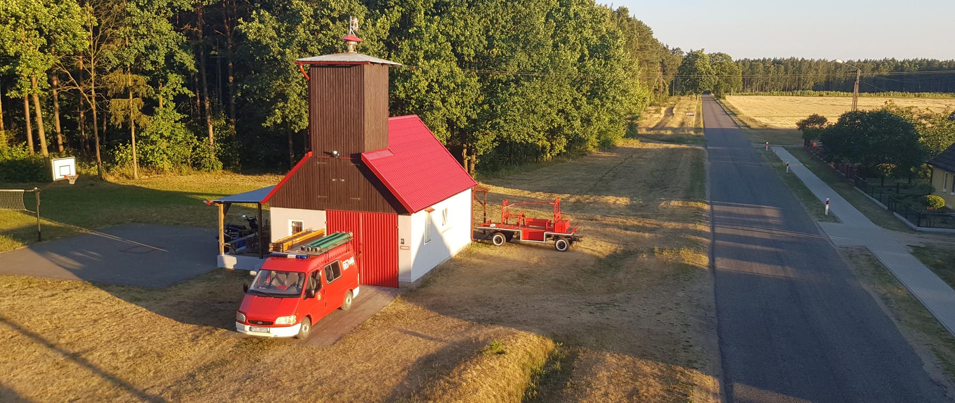 Widok remizy z pojazdem i zabytkowym pożarniczym wozem konnym