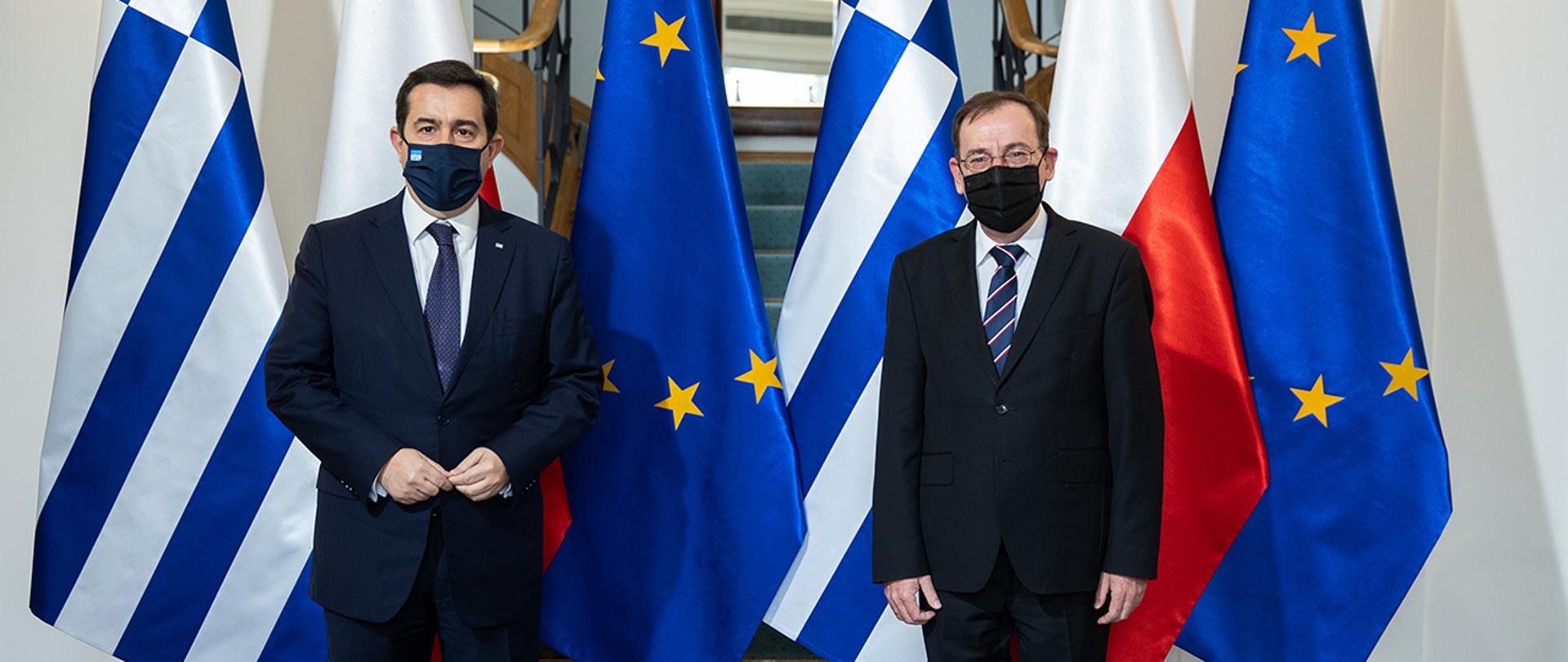 Na zdjęciu widać ministra Mariusza Kamińskiego i ministra ds. migracji i azylu Grecji Notisa Mitarachi stojących na tle flag Polski, Gracji i UE.
