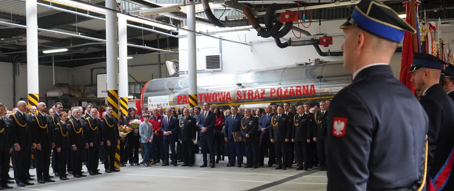 Zdjęcie zrobione na hali garażowej. Na zdjęciu uczestnicy uroczystości. 