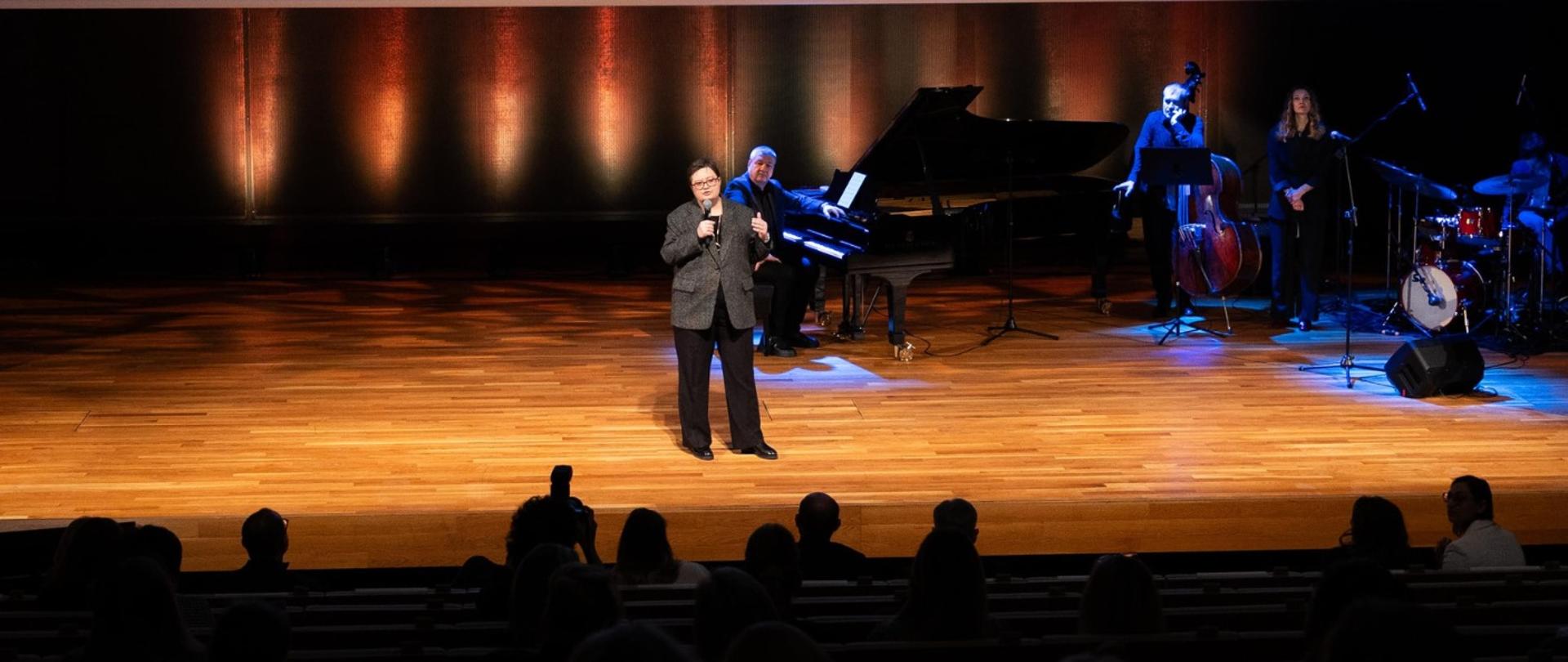 Widok na scenę na której stoi wiceminister Lubnauer i przemawia do mikrofonu