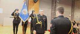Nadbryg. Piotr Filipek odbiera decyzję personalną od KG PSP, w tle poczet sztandarowy SA PSP 