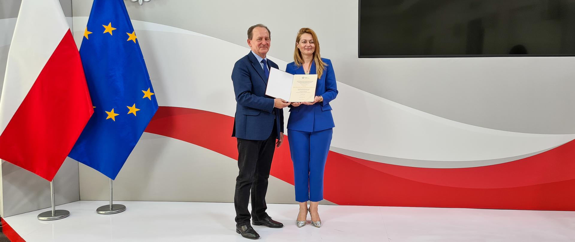 wiceminister Włodzimierz Bernacki wręcza powołania poszczególnym członkom do zespołu obsługi programu, Rozwój czasopism naukowych. Z prawej strony stoi rzecznik prasowa i wyczytuje listę powołanych osób