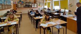 Eliminacje ogólnopolskiego turnieju wiedzy pożarniczej. Dzieci siedzą w ławkach w klasie i piszą testy 