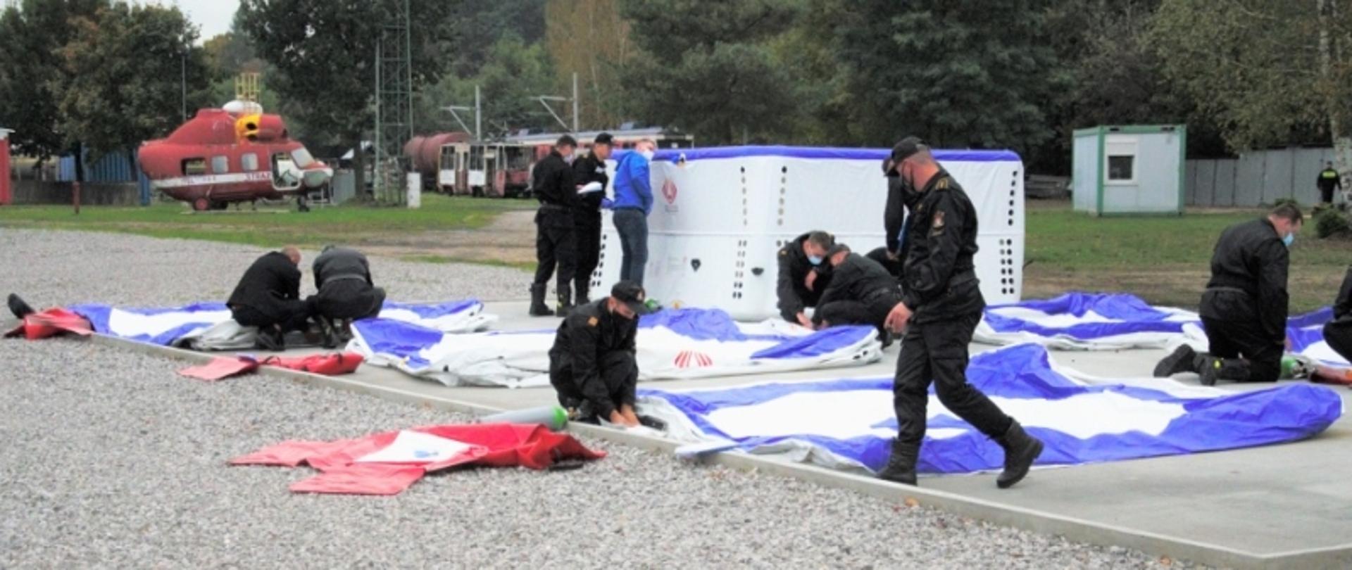 Odbiór skokochronów. Na zdjęciu strażacy rozkładający skokochrony na utwardzonym placu.