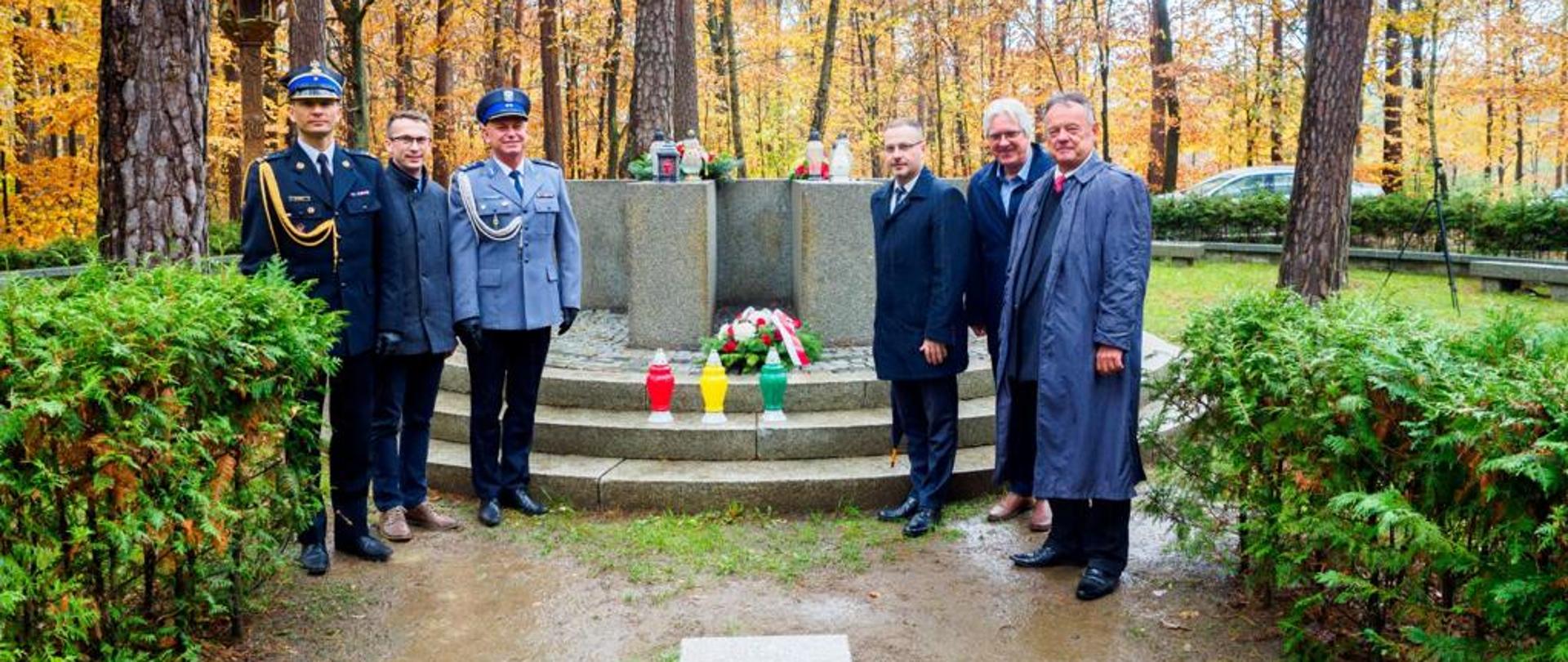 Na zdjęciu delegacja stojąca przy pomniku poległych lotników litewskich. Wokół las.