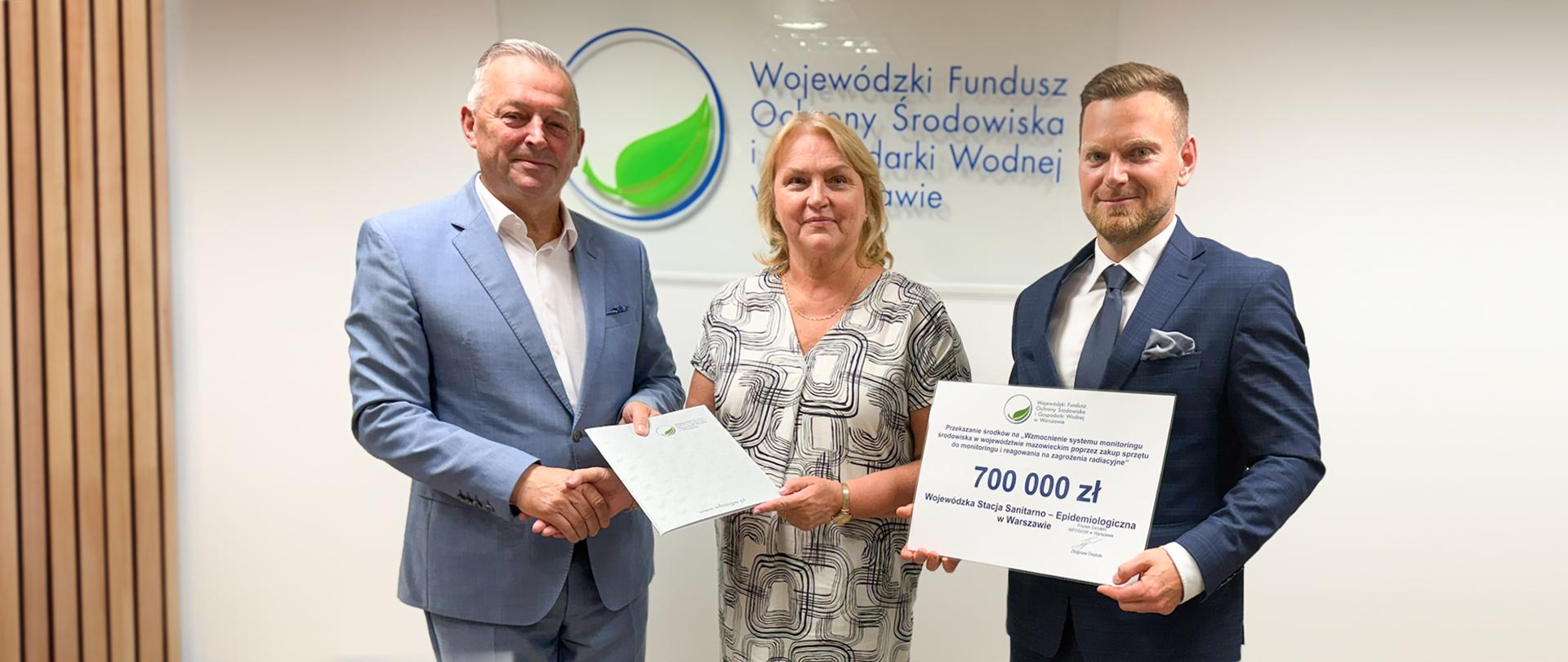 Prezes Zarządu WFOŚiGW oficjalnie wręcza Dyrekcji WSSE w Warszawie dokumenty dotyczące dofinansowania na zakup specjalistycznego sprzętu do monitorowania zagrożeń radiacyjnych.