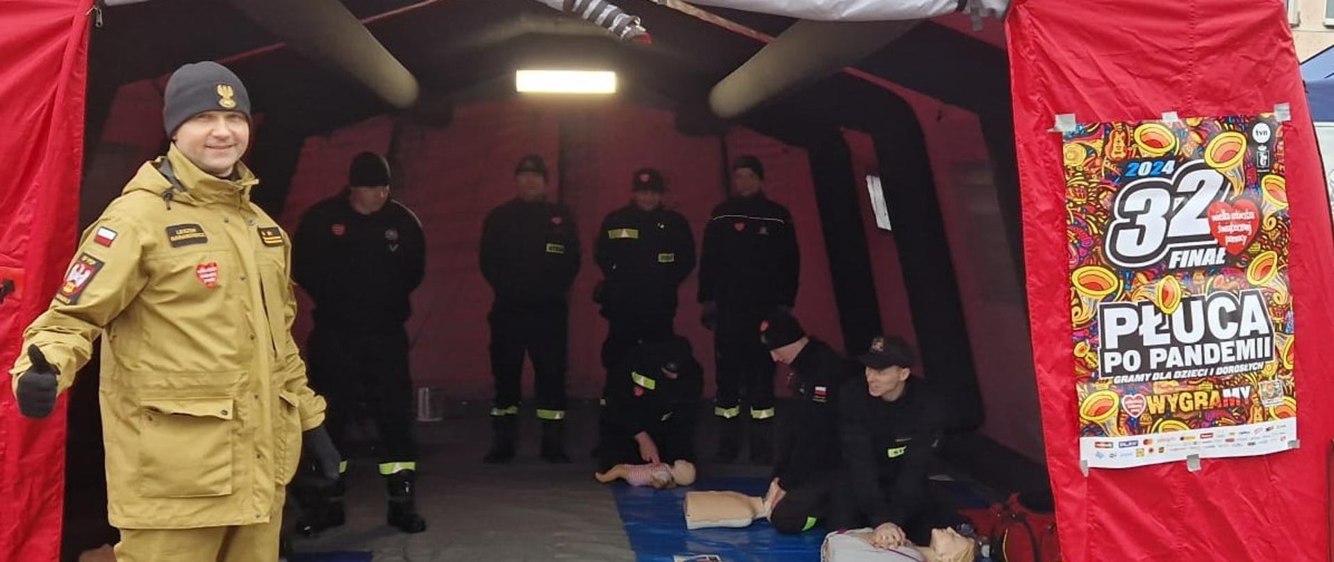 Zdjęcie przedstawia strażaków w trakcie 32. finału Wielkiej Orkiestry Świątecznej Pomocy.
W tle rynek chodzieski i budynki.
