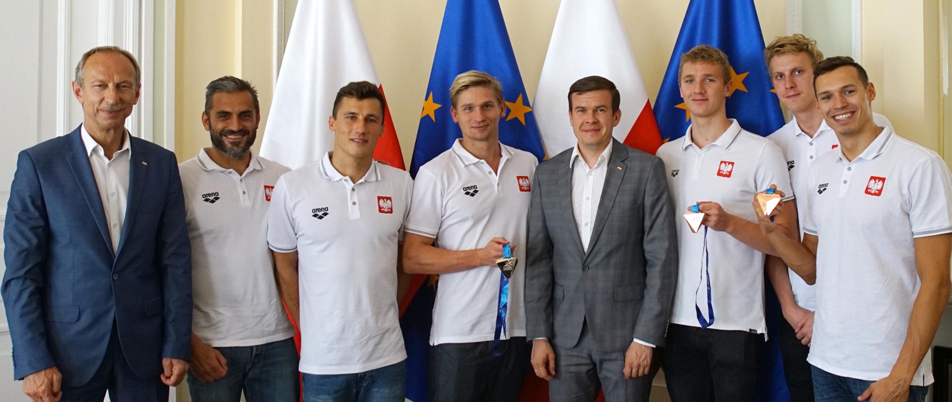 wizyta_medalistów_Glasgow_-_pływanie,_muszlowa_12_zdjęcie_grupowe_sportowców_z_ministrem_Bańką_i_Widerą