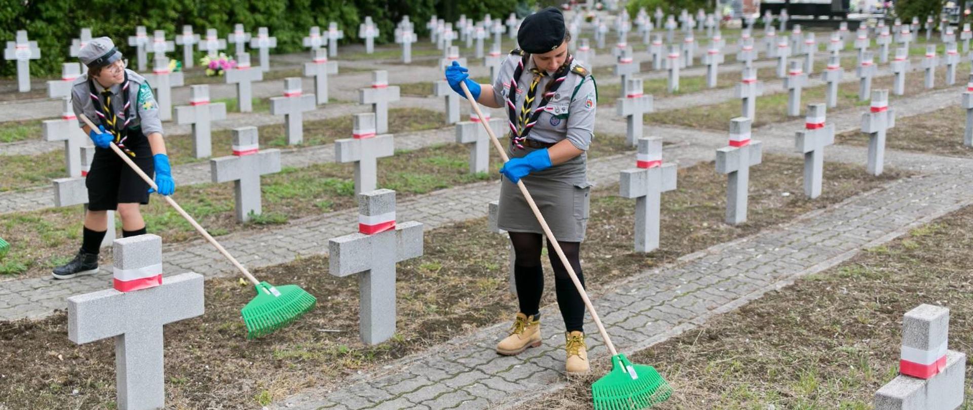 Dwie harcerki porządkują groby żołnierzy Armii Krajowej 