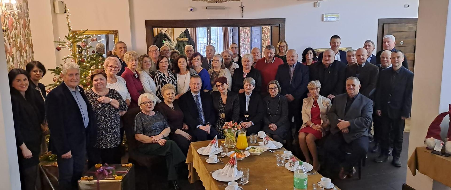 Pamiątkowe zdjęcie uczestników Wigilii, w tle choinka.