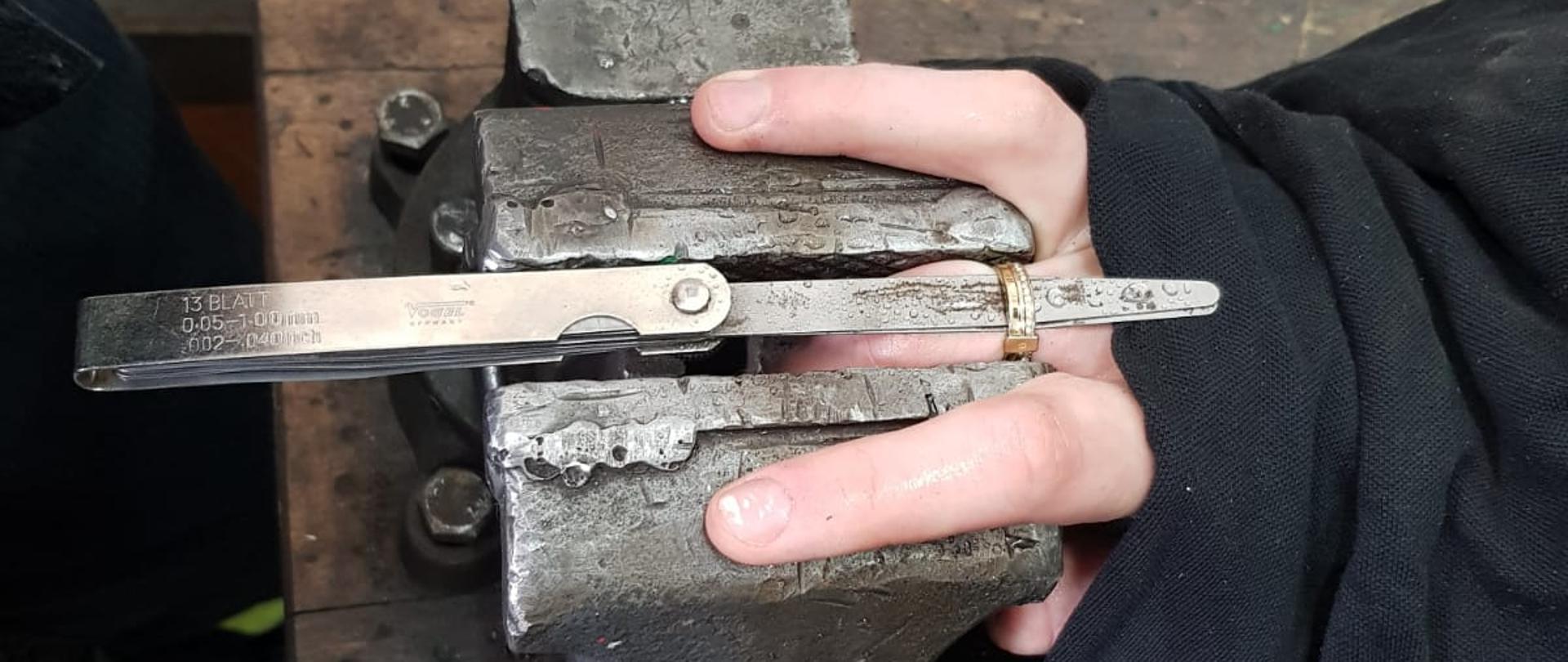Na zdjęciu widać imadło z zaciśniętą obrączką oraz zabezpieczoną ręką, gotowe do przecięcia
