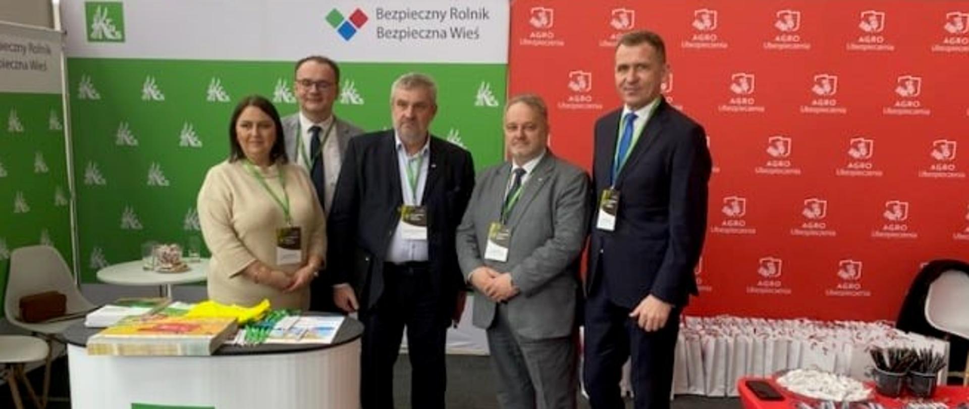 Grupa osób na tle stoiska informacyjnego