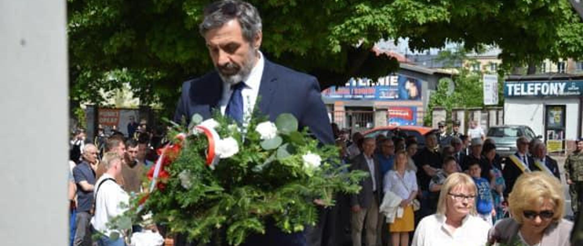 Zdjęcie: dyrektor PLSP składa wiązankę , w tle uczestnicy uroczystości 3 maja