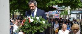 Zdjęcie: dyrektor PLSP składa wiązankę , w tle uczestnicy uroczystości 3 maja