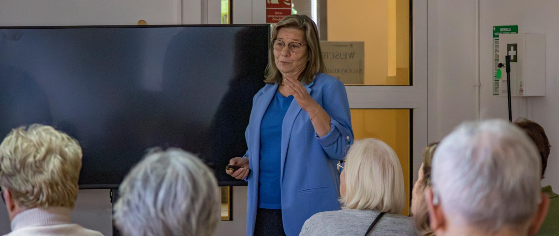 Bryg. w st. spocz. dr Anna Obolewicz prowadzi wykład "Bezpieczeństwo pożarowe w domu" przed nią siedzi na krzesłach grupa seniorów