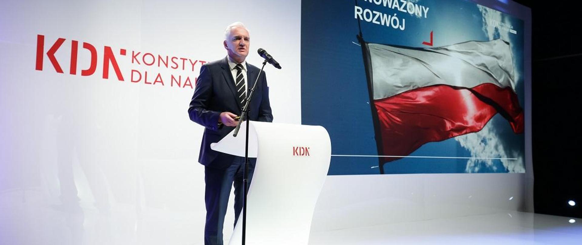 Minister Gowin przemawia na tle ściany z napisem KDN