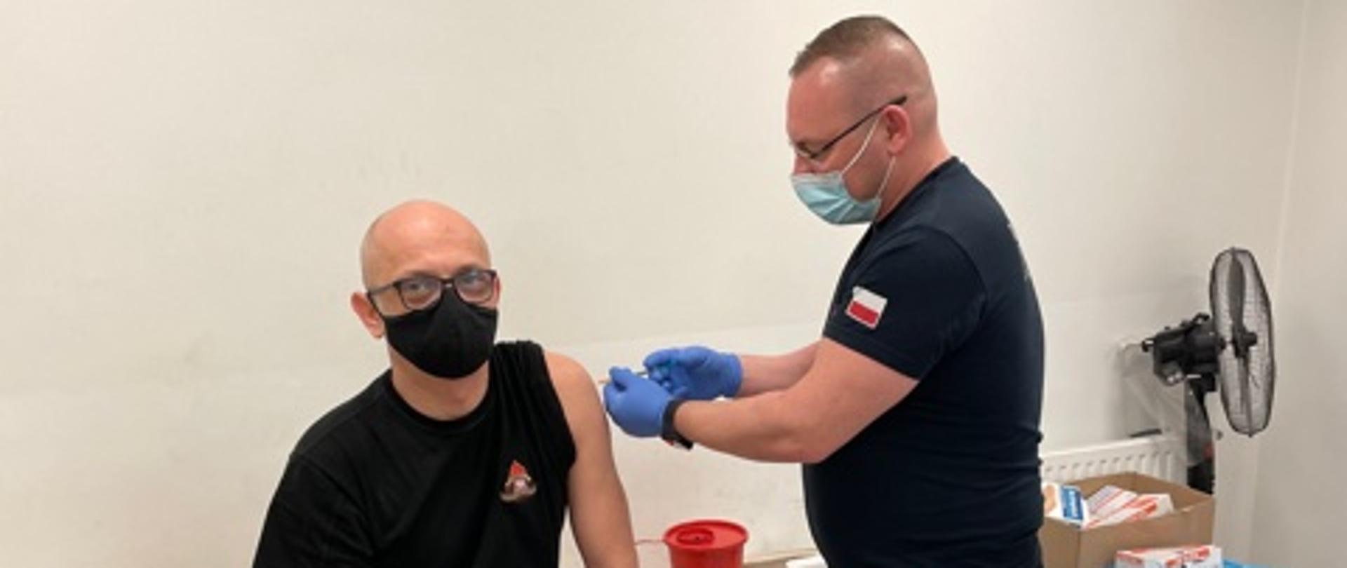 Na zdjęciu strażak PSP podczas szczepienia w punkcie szczepień