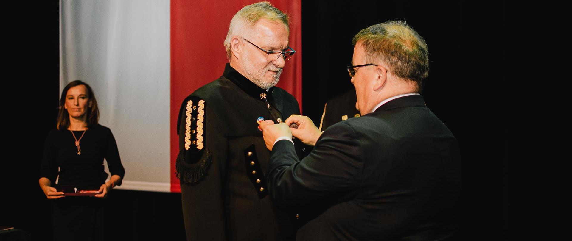 Prezes WUG dr inż. Adam Mirek otrzymuje Krzyż Kawalerski Orderu Odrodzenia Polski (w tle flaga biało-czerwona)