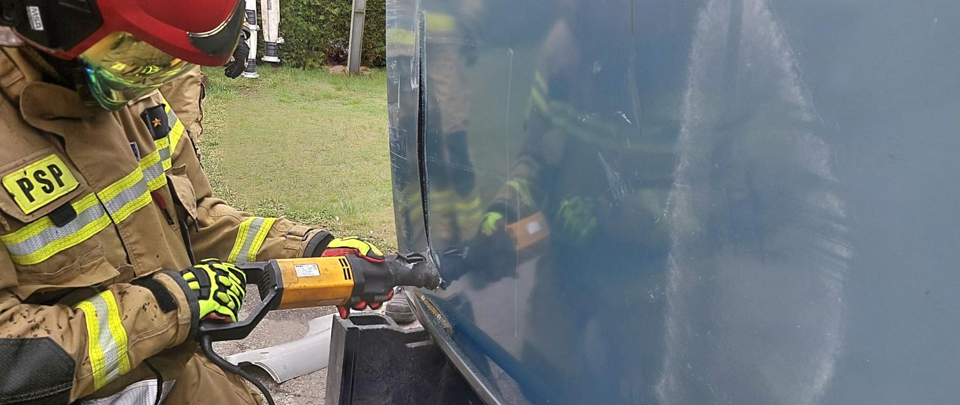 Strażak przecina dach pojazdu