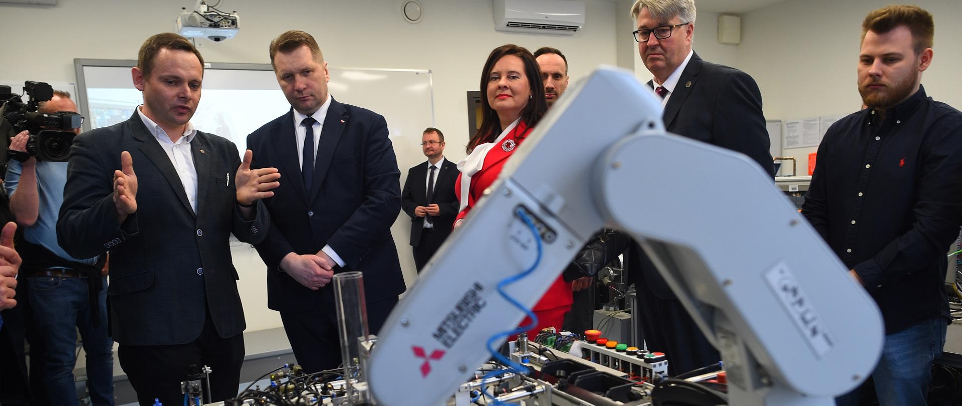 Wizyta na Politechnice Opolskiej. Minister ogląda ramię robota.
