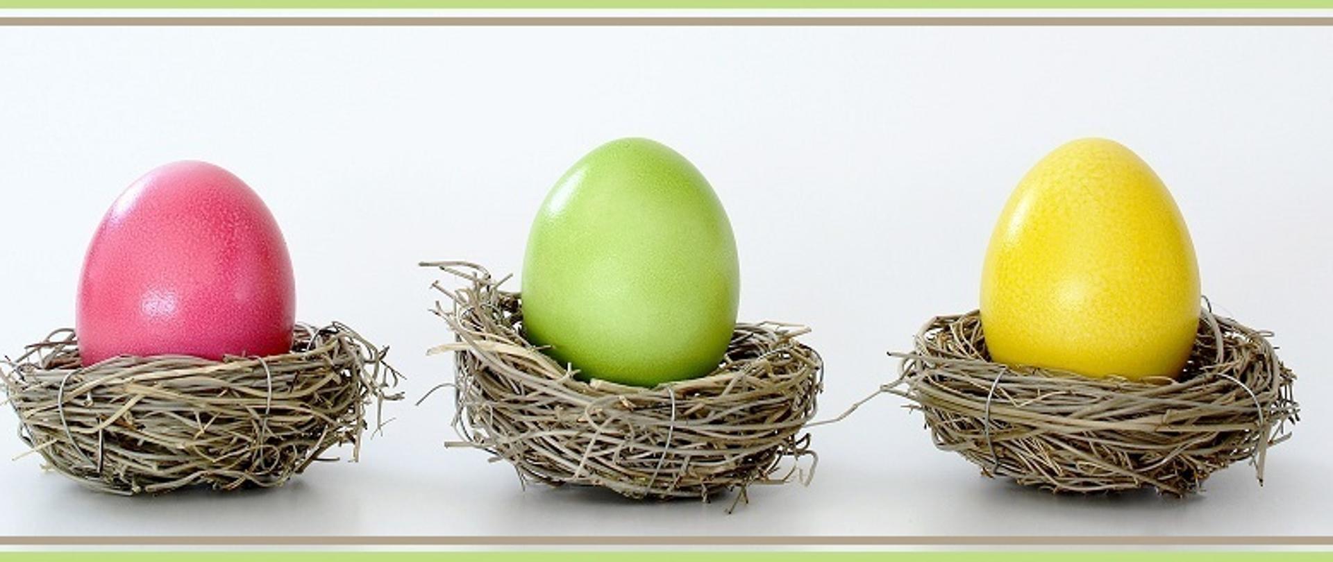 kartka świąteczna przedstawiająca 3 kolorowe pisanki w gniazdach ptasich