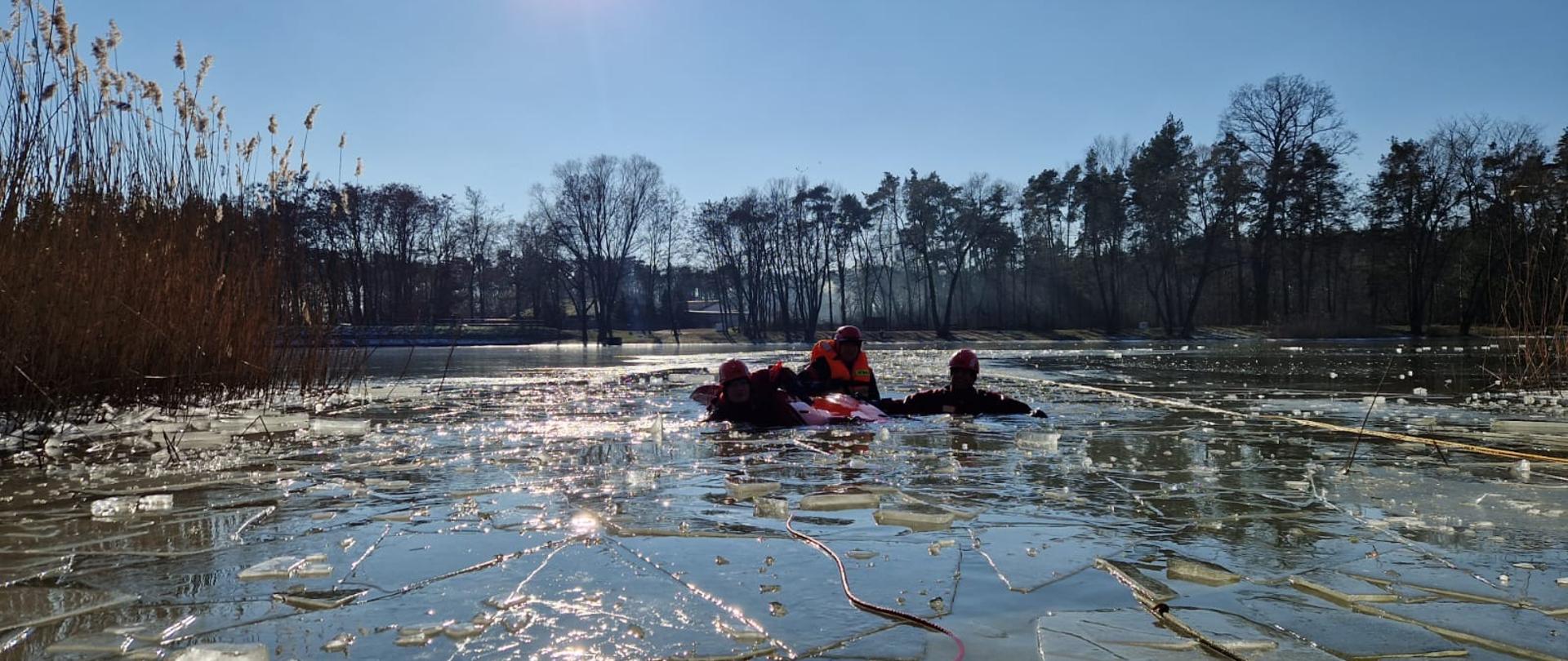 Strażacy w kombinezonach w zbiorniku wodnym 