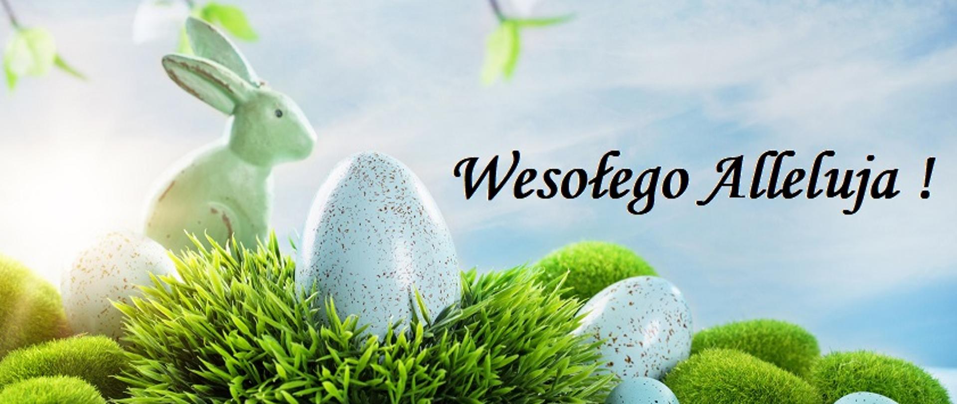 Grafika wielkanocna przedstawiająca bladoniebieskie pisanki i króliczka na zielonej trawie