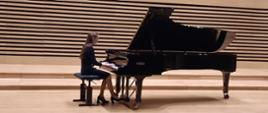 Uczennica grająca na fortepianie na scenie sali koncertowej PSM