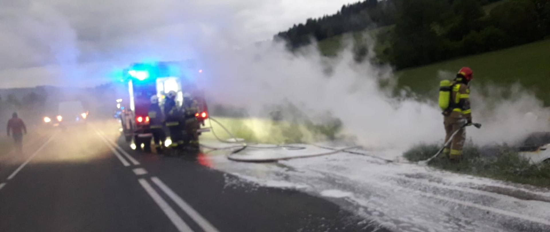 Dym wydobywający się z palącego się samochodu w rowie.